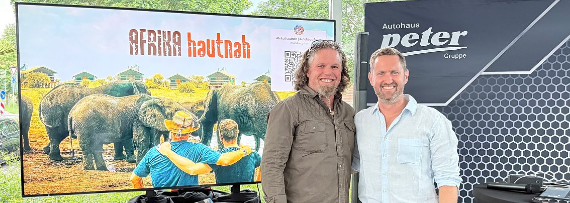 Guide Hannu und Patrick vor Bildschirm mit Afrika-Motiv 