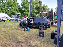 SUV mit Besuchern: Schwarzer Mercedes-Benz SUV, in den eine Frau mit Kind hineinschaut, umgeben von weiteren Ausstellungsflächen. (Foto: Autohaus Peter GmbH)