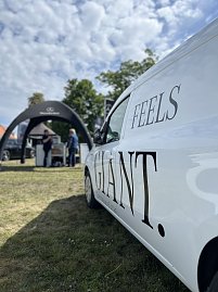Weißer Transporter mit Schriftzug: Seitliche Nahaufnahme eines weißen Fahrzeugs mit dem Schriftzug „Feels Giant“ auf der Messefläche. (Foto: Autohaus Peter GmbH)