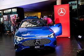 Ein blauer Mercedes CLA wird im Showroom präsentiert. Mehrere Besucher betrachten das Auto, während ein Mann in den Innenraum schaut. (Foto: Buchardt | Autohaus Peter )