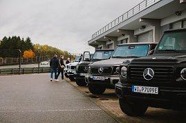 Noch einmal eine professionelle Aufnahme aller G-Klassen Modelle aufgereiht im sauberen Zustand vor der G-Klassen experience. Einige Teilnehmer schauen sich zudem die Modelle an. [Mercedes-Benz G 580 mit EQ Technologie | Energieverbrauch kombiniert: 30,3-27,7 kWh/100 km | CO2;-Emissionen kombiniert: 0 g/km | CO2;-Klasse: A] [Mercedes-AMG G 63 | Energieverbrauch kombiniert: 15,7-14,7 l/100 km | CO2;-Emissionen kombiniert: 358-335 g/km | CO2;-Klasse: G] 