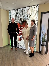 Bürgermeister, Landrätin und Ärztin stehen vor beleuchtetem XXL Wandbild und lächeln in die Kamera