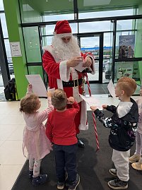 Die Kinder geben dem Weihnachtsmann ihre gemalten Wunschzettel