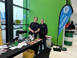 Zwei Polizistinnen stehen an einem Infostand mit Buttons und Malmaterial, daneben Banner Thüringer Polizei.