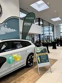 Weißer Skoda im Autohaus mit Ballons, daneben Aufsteller Gewinnspiel und Skoda-Peter-Beachflag im Hintergrund.