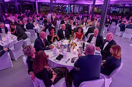 G&auml;ste sitzen an gedeckten Tischen bei Gala-Event mit stimmungsvoller Beleuchtung.