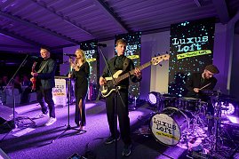 Eine Live-Band sorgt f&uuml;r Stimmung: S&auml;ngerin, Gitarrist, Bassist und Schlagzeuger stehen auf einer B&uuml;hne mit moderner Lichttechnik und performen vor den G&auml;sten. Im Hintergrund mehrere Displays mit der Aufschrift Luxus Loft � Die Party WG.