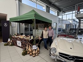 Der Stand vom Wildgourmet, bestehend aus einem gr&uuml;nen Pavillon und einem Stand mit Fleisch. Die Verk&auml;ufer stehen neben einem Mercedes-Benz Oldtimer.