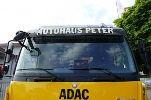 Frontansicht eines gelben ADAC-Abschleppwagens mit der Aufschrift AUTOHAUS PETER &uuml;ber der Windschutzscheibe und dem ADAC-Logo.