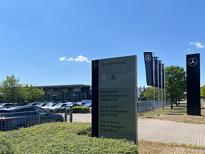 Gro&szlig;es Schild vor dem Mercedes-Benz Autohaus Peter in Dessau. Auf dem Schild stehen die Bereiche: Verkauf, Service, Teile/Zubeh&ouml;r, Gebrauchtwagen, Junge Sterne. Oben Logos von Mercedes-Benz und Fuso. Im Hintergrund das Autohaus.