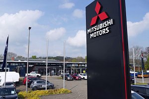 Au&szlig;enansicht des Peter-Mehrmarkenhauses in G&ouml;ttingen mit gro&szlig;em Mitsubishi-Motors-Schild im Vordergrund und mehreren Fahrzeugen auf dem Parkplatz.