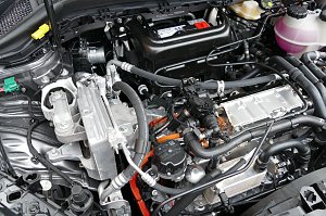 Blick in den Motorraum eines E-Fahrzeuges. Gut zu erkennen sind die Hochvolt-Trennstelle (grün) und die HV-Kabel (orange).