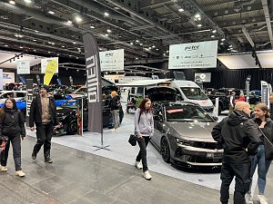Blick auf mehrere Opel-Fahrzeuge, darunter ein grauer Opel mit offener Motorhaube und ein Wohnmobil. Besucher laufen &uuml;ber die Messefl&auml;che.