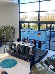 Blick leicht von oben auf Podiumsdiskussion mit vier Teilnehmenden, darunter Colette Boos-John. Vor der B&uuml;hne gro&szlig;e schwarze CDU-Buchstaben, im Hintergrund ein Skoda-Auto.