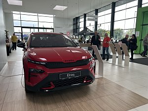 Ein roter Škoda Elroq steht im Ausstellungsraum des Autohauses Autowelt Peter. Im Hintergrund stehen und unterhalten sich mehrere Besucher, daneben befinden sich Infostände und ein Bereich mit Sitzgelegenheiten.