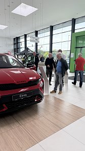 Ein roter Škoda Elroq steht im Ausstellungsraum. Mehrere Besucher stehen daneben und informieren sich an den Infostelen.