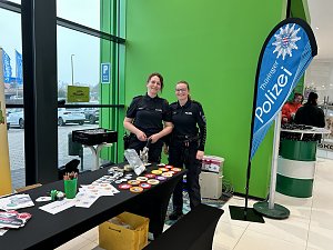 Zwei Polizistinnen stehen an einem Infostand mit Buttons und Malmaterial, daneben Banner Th&uuml;ringer Polizei.