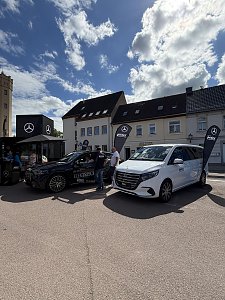 Man sieht unseren Promotion-Stand mit einem schwarzen GLC und einer weißen V-Klasse.