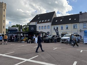 Man sieht unseren Promotion-Stand mit einem grauen Actros, einem schwarzen GLC und einer weißen V-Klasse.
