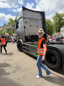 Kati Bergmann, Serviceassistentin in Bernburg, läuft als Radengel in orangener Warnweste neben dem eActros.