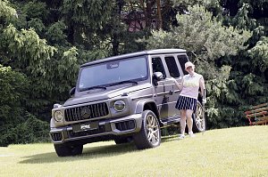 Teilnehmerin posiert lächelnd neben einer ausgestellten Mercedes G-Klasse auf dem Golfplatz.