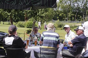 Teilnehmer sitzen an einem Tisch auf der Terrasse mit Blick auf den Golfplatz.