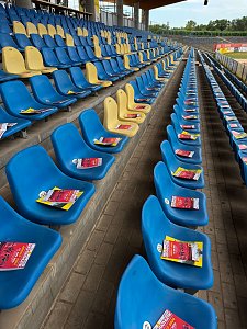Die blauen und gelben Sitzschalen der Stadiontrib&uuml;ne, auf denen Flyer f&uuml;r das Leichtathletikmeeting ANHALT 2026 f&uuml;r die Zuschauer bereitliegen.