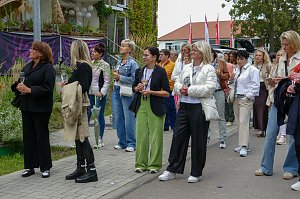 Eine gr&ouml;&szlig;ere Gruppe von Frauen, die im Freien auf einem Gehweg stehen und gemeinsam aufmerksam in eine Richtung blicken.
