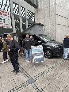 Man sieht einige Zuschauer, im Fokus des Bildes steht der Marco Polo, davor steht ein A1-Kundenstopper.