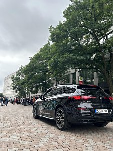Man sieht den vollelektrischen GLC in Schwarz auf der Strecke. Auf der Seite des Fahrzeugs ist Werbung aufgeklebt. Man erkennt den Schriftzug "ELEKTRISCHE GLC" und einen blauen Netzstecker.