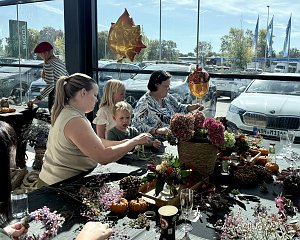 Besucherinnen und Kinder gestalten gemeinsam mit Flower Power herbstliche Kränze aus Blumen und Naturmaterialien beim Škoda BEST DAY.