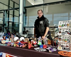 Aussteller hinter einem Verkaufsstand mit handgefertigten Dekorationsartikeln, Figuren und bunten Schlüsselanhängern beim Aktionstag der Autowelt Peter.