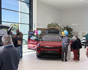Besucher informieren sich im Škoda-Showroom über den roten Škoda Elroq mit geöffneten Türen und geöffneter Heckklappe.