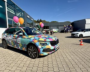 Farbenfroh folierter Škoda mit buntem Luftballonmotiv auf dem Außengelände der Autowelt Peter, im Hintergrund Hüpfburg und Veranstaltungsbereich.