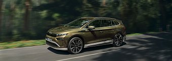 �koda Enyaq (Seitenansicht) f&auml;hrt schnell auf einer Stra&szlig;e durch den Wald. (�koda Auto Deutschland GmbH)