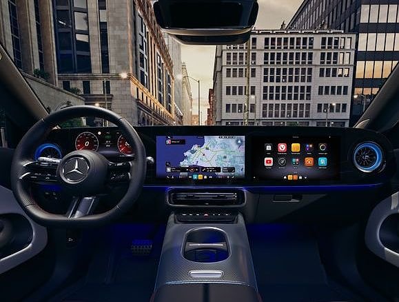 Das Bild zeigt das Interieur des neuen Mercedes-Benz CLA Shooting Brake. Moderne Gebäude umgeben die Szene, das Licht wirkt weich und frühmorgendlich. 