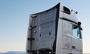R&uuml;ckseite des Lkw-Fahrerhauses in Silber von der Seite. Auf der Verkleidung ist der geschwungene Schriftzug Actros aufgepr&auml;gt. Blauer Himmel.